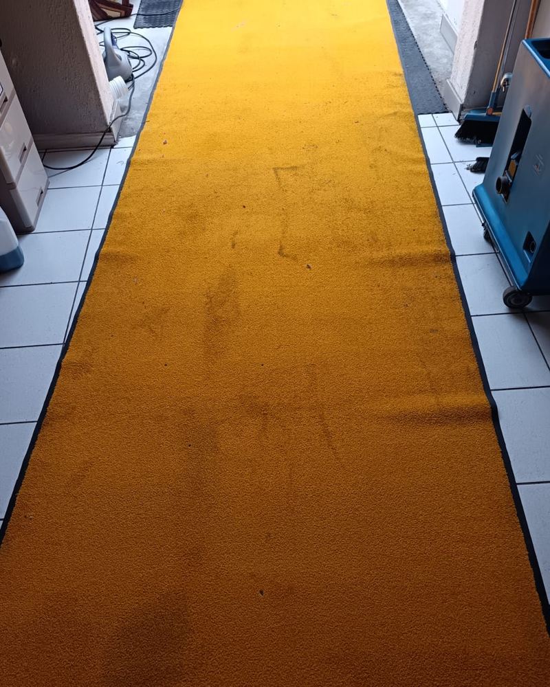 Dirty yellow entrance runner with footprint stains before cleaning