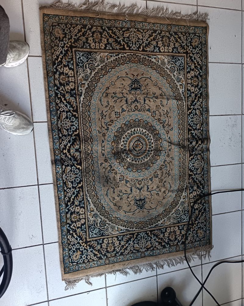 Persian-style rug with dull, dirty patches before cleaning